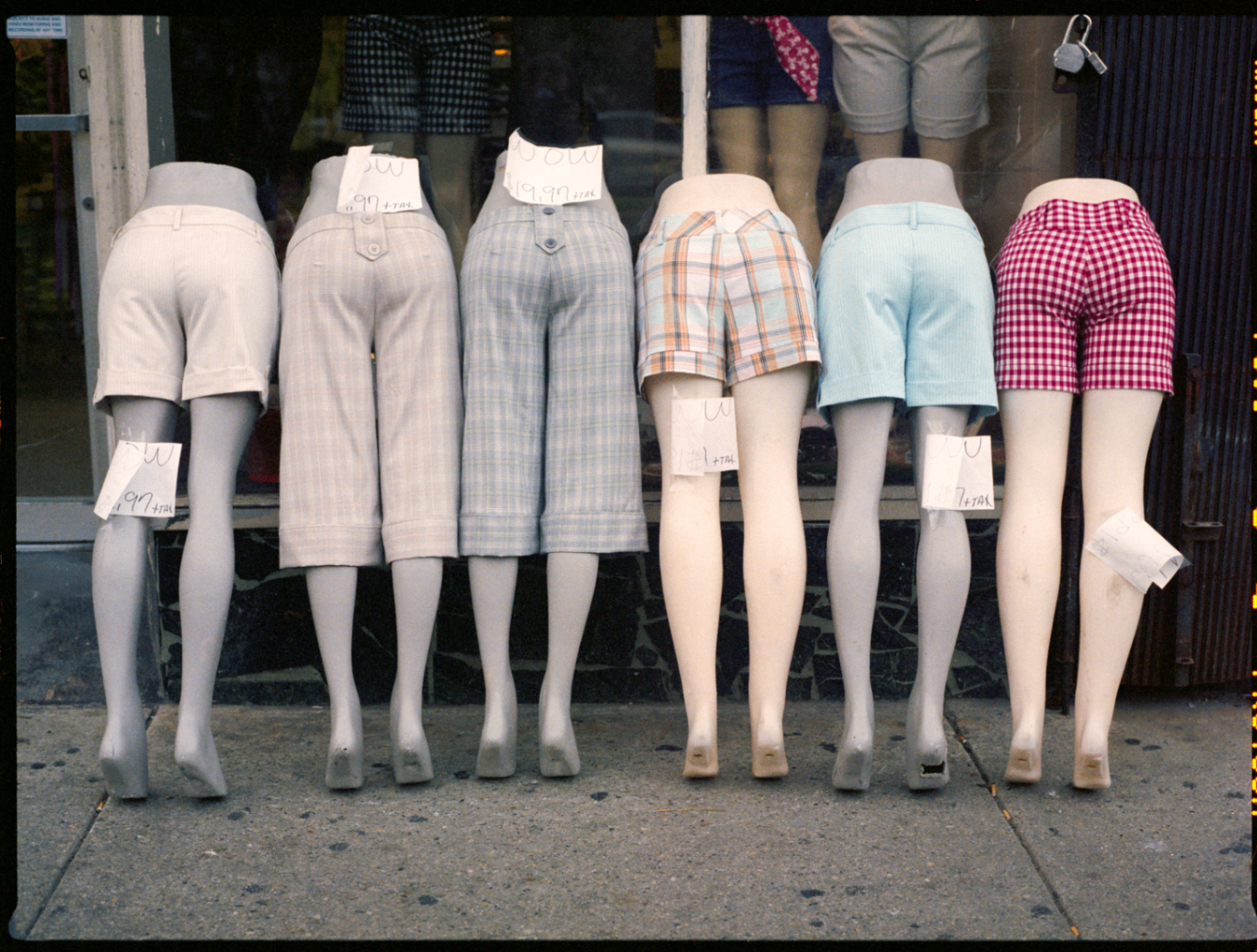 Storefront display of mannequin legs wearing patterned shorts